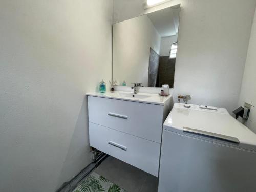 a white bathroom with a sink and a mirror at Appartement bord de mer Kay Dominik in Le Robert