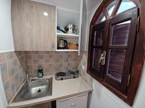 a small kitchen with a sink and a window at Evelina Family Beach Pension a breath away from the Black Beach offer plenty of accommodation type to suit every traveler's needs-Economic Rooms-Thematic Rooms-Design Rooms-Kitchenette Rooms-Studios-Small Apartments in Perissa