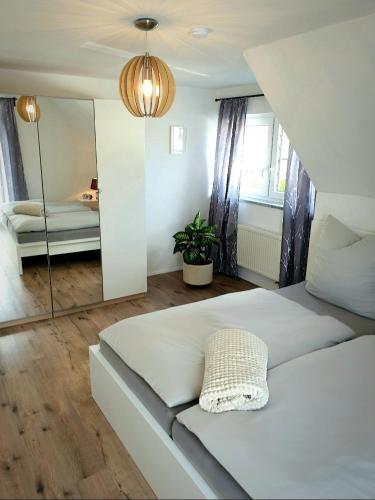 - une chambre avec un grand lit blanc et un miroir dans l'établissement Ferienhaus - Am Waldrand, 