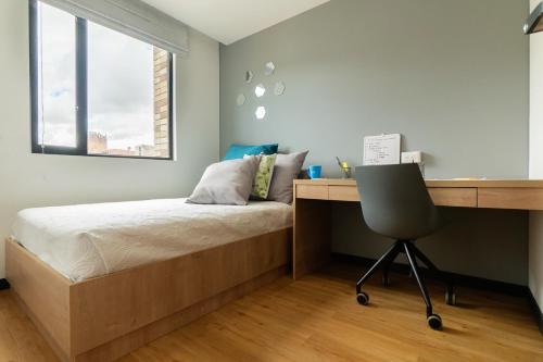 a bedroom with a bed and a desk and a chair at CentralX 21 Bogotá in Bogotá