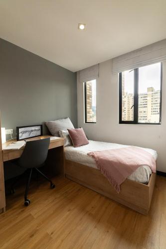a bedroom with a bed and a desk with a desk at CentralX 21 Bogotá in Bogotá