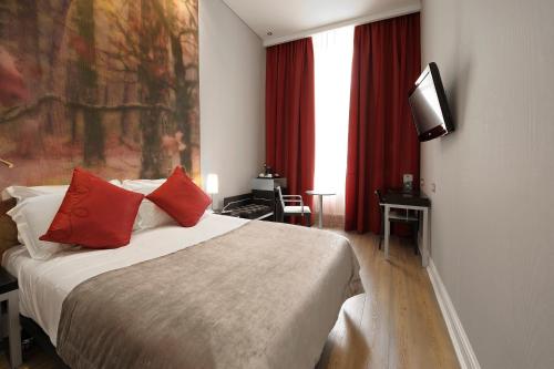 een slaapkamer met een bed met rode kussens en een televisie bij The Queens Gate Hotel in Londen