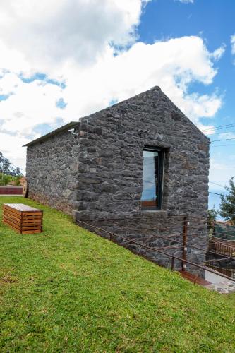 a stone building with a window in the grass at House Nobrega of Madeira in Arco da Calheta