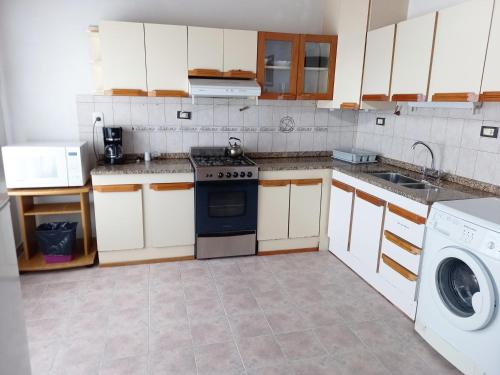 a kitchen with a stove and a washing machine at La hogareña in El Calafate