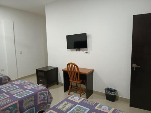 a bedroom with a bed and a desk and a tv at Hotel Romo in Los Mochis