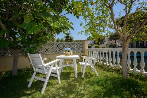 a white table and chairs in a yard with a fence at Casa Fluvia in Empuriabrava