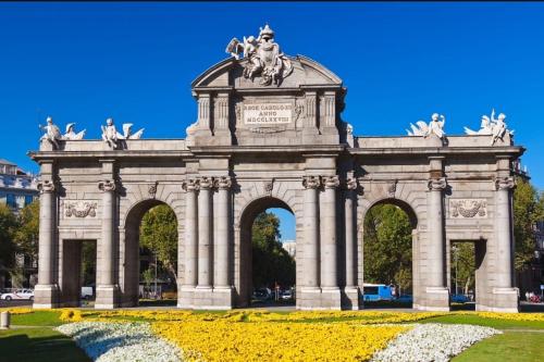 a large monument in a park with yellow flowers at Hostal Vara Madrid in Madrid