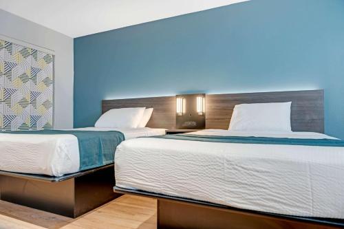 two beds in a room with blue walls at Studio 6 Suites Stockton, CA Waterfront in Stockton
