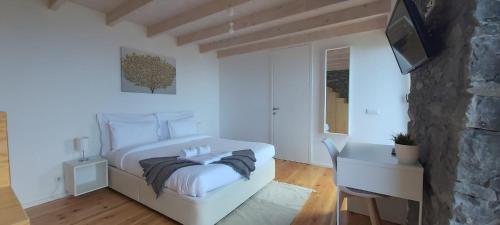 a white bedroom with a bed and a television at House Nobrega of Madeira in Arco da Calheta