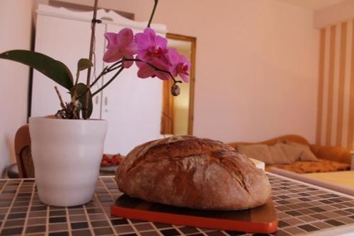 a loaf of bread and a vase with flowers on a table at Villa Bougenvilia Tomas in Tučepi