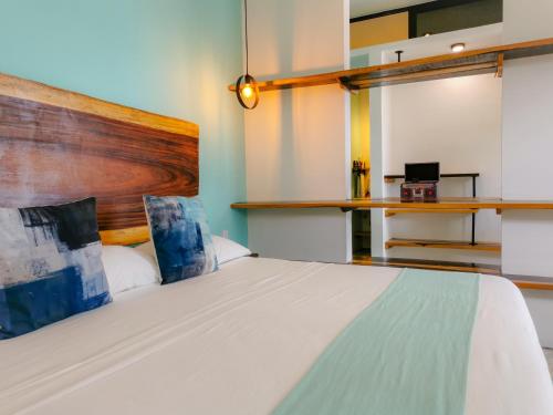 a bedroom with a large white bed with a wooden headboard at Les Suites Calle 2 by Galian in Tulum