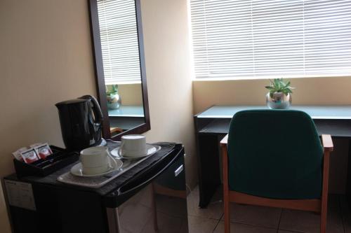 a room with a desk with a coffee maker and a chair at Sunnyridge Lodge in East London