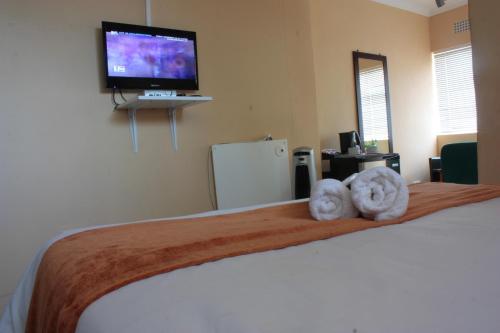 a bedroom with a bed with two towels on it at Sunnyridge Lodge in East London