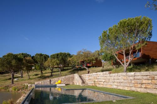 a pool of water with a stone retaining wall at Herdade do Moinho Novo in Canha