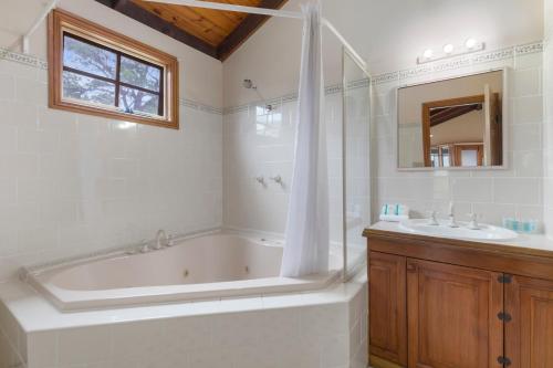 a white bathroom with a tub and a sink at Wairo Beach Holiday Park in Lake Tabourie