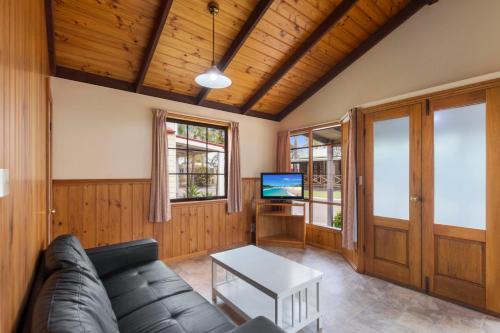 a living room with a couch and a tv at Wairo Beach Holiday Park in Lake Tabourie
