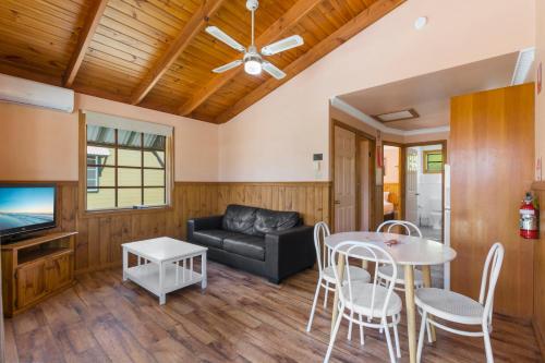 a living room with a couch and a table at Wairo Beach Holiday Park in Lake Tabourie