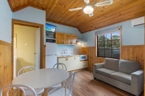 a kitchen and living room with a table and a couch at Wairo Beach Holiday Park in Lake Tabourie