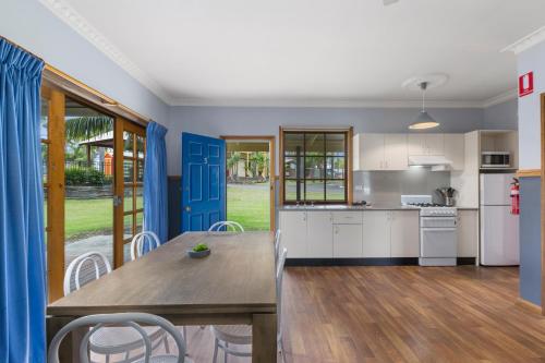 a kitchen and dining room with a table and chairs at Wairo Beach Holiday Park in Lake Tabourie