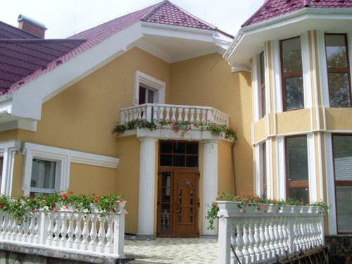 a yellow house with a white fence in front of it at Gnizdo Golubky in Shaian