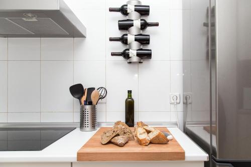 Una cocina con una tabla de cortar con pan y botellas de vino. en Sol - 5 Tirso de Molina - ALQUILER CORTA ESTANCIA, en Madrid