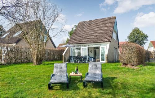 a house with two chairs and a table in the grass at Lovely Home In Vlagtwedde With Sauna in Vlagtwedde