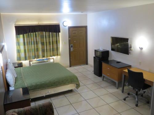 Habitación de hotel con cama, escritorio y TV. en Executive Inn Laguna Vista, en Laguna Vista