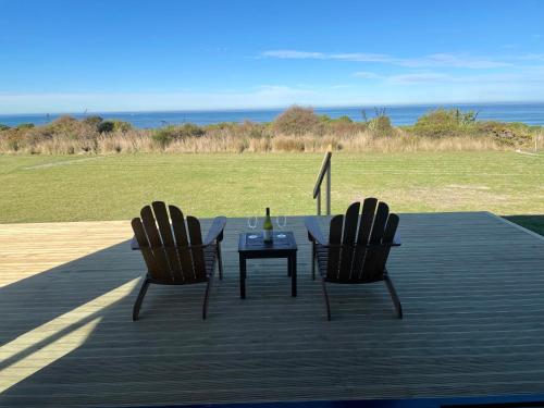 two chairs and a table on a deck at Toko Mouth Beach House in Glenledi