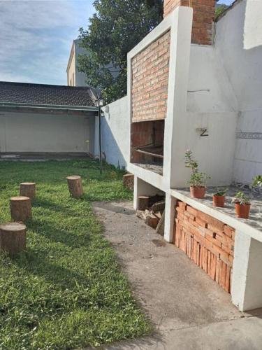 a backyard with a brick wall next to a house at Casa Frente Parque Guillermina in San Miguel de Tucumán