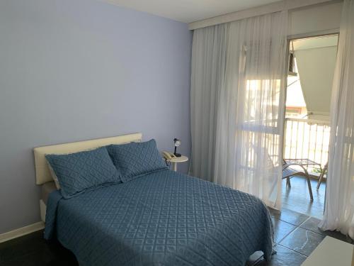a bedroom with a blue bed and a balcony at Excelente Apart Hotel Ipanema in Rio de Janeiro