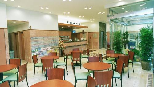 un restaurant avec des tables en bois et des chaises vertes dans l'établissement Toyoko Inn Ueda Ekimae, à Ueda