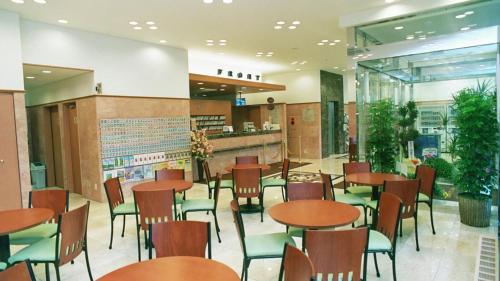 a restaurant with wooden tables and green chairs at Toyoko Inn Ueda Ekimae in Ueda