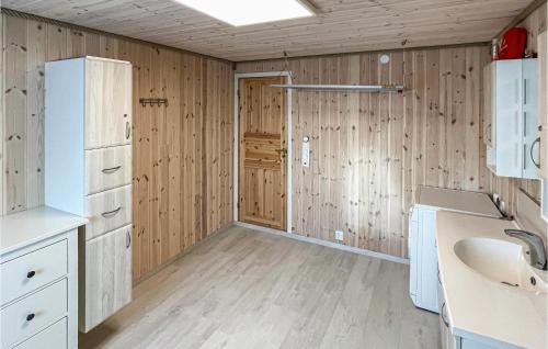 cocina con paredes de madera, lavabo y puerta en 5 Bedroom Amazing Home In Nedstrand en Nedstrand