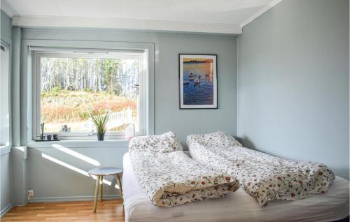 a bedroom with a bed with pillows and a window at Beach Front Home In Bvgen With House Sea View in Bøvågen