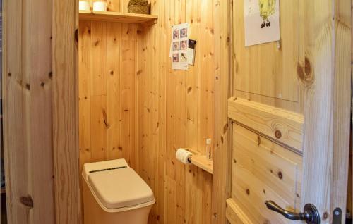a bathroom with a toilet and a wooden wall at Lovely Home In Espedalen With Kitchen in Espedalen