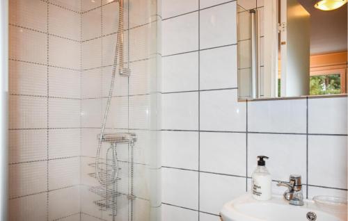 a white tiled bathroom with a shower and a sink at 1 Bedroom Amazing Home In Hllviken in Höllviken