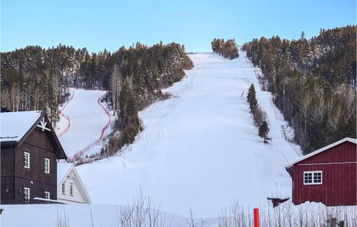 a snow covered hill with a red barn and a ski slope at Stunning Home In Uvdal With Wifi in Uvdal