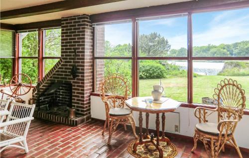 a screened in porch with a table and chairs and a fireplace at Lovely Home In Brkne-hoby With House Sea View in Bräkne-Hoby