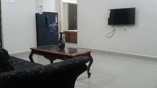 uma sala de estar com um sofá, uma mesa e uma televisão em GIRI Service Apartment em Tirupati
