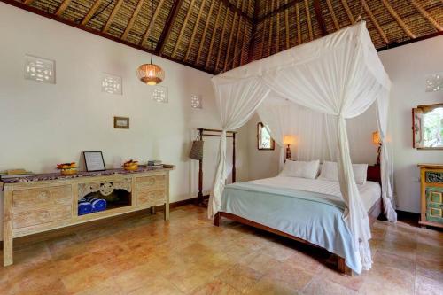 a bedroom with a bed with a canopy at Rumah Kelapa Senang in Karangasem