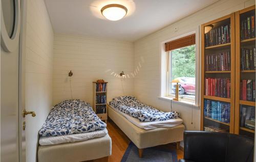 Zimmer mit 2 Betten, einem Fenster und Bücherregalen in der Unterkunft Awesome Home In Mellerud With Lake View in Mellerud