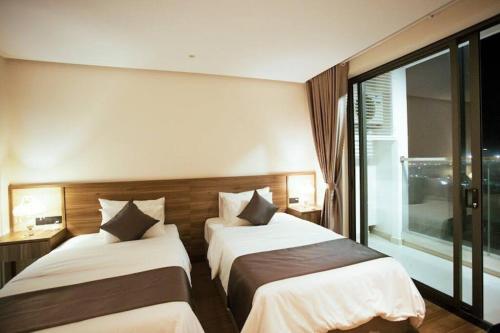 una camera d'albergo con due letti e una finestra di Apec 5 sao TP.Tuy Hòa - View biển và view hồ bơi a Ðông Tác (1)