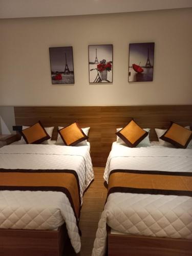 two beds in a room with pictures on the wall at Apec 5 sao TP.Tuy Hòa - View biển và view hồ bơi in Ðông Tác (1)