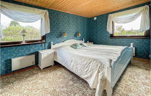 a blue bedroom with a bed and two windows at Amazing Home In Höviksnäs With Kitchen in Höviksnäs
