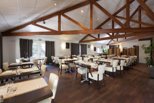 a dining room with tables and chairs and wooden ceilings at Logis Le Relais de Sassenage in Sassenage