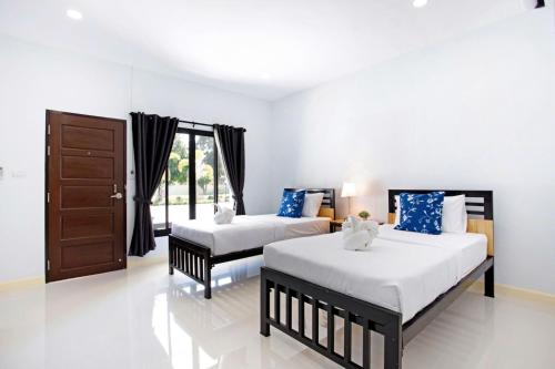 a bedroom with two beds and a door at Srida Resort Lanna and Cafe in Chiang Mai