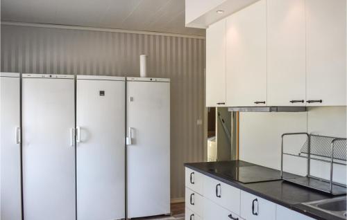 a kitchen with white cabinets and black counter tops at Cozy Home In Klockrike With Wifi in Klockrike