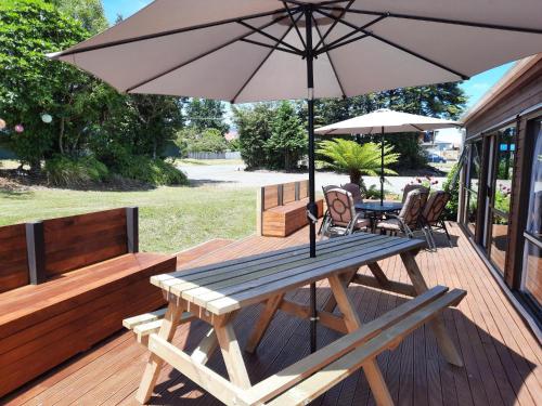 una terraza de madera con mesa de picnic y sombrilla en Manowhenua Lodge, en National Park