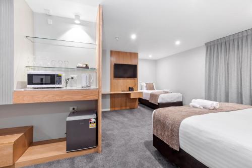 a hotel room with two beds and a tv at Kolmar Inn in Auckland