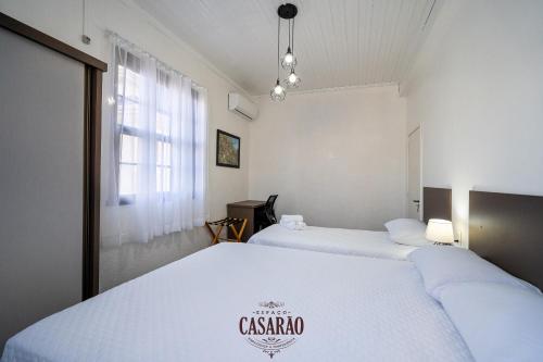 two beds in a room with white walls and a window at Espaço Casarão - Serra Gaúcha in Cotiporã